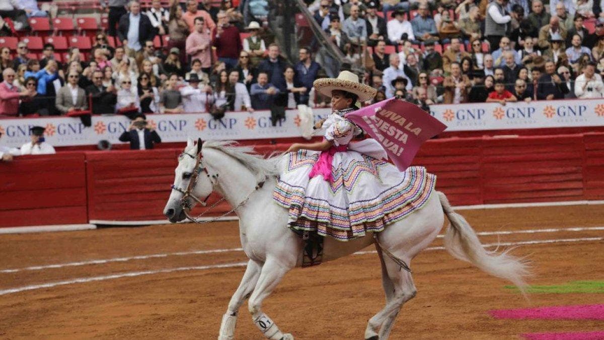 A girl rides a white horse in the bullring in Mexico City