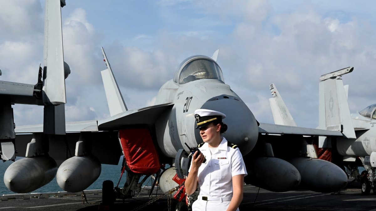 Una efectivo de la Armada estadounidense se encuentra junto a un avión en la cubierta del portaaviones USS George Washington.