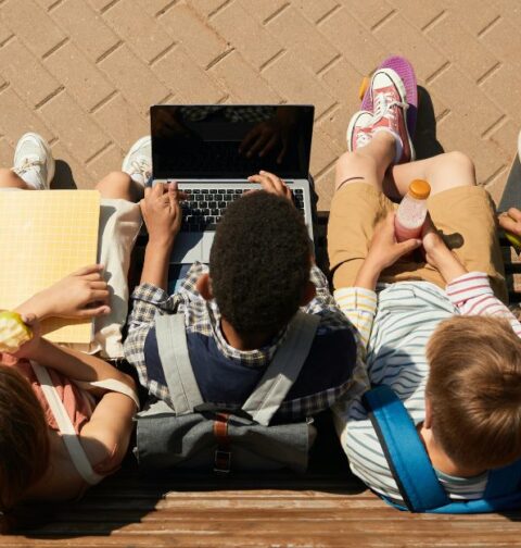 Varios niños observan un ordenador en una escuela.