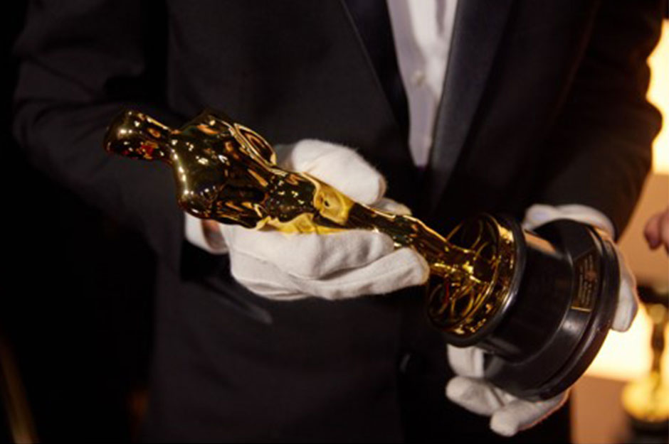 One of the Oscars Awards being held by the man in charge of custoding them
