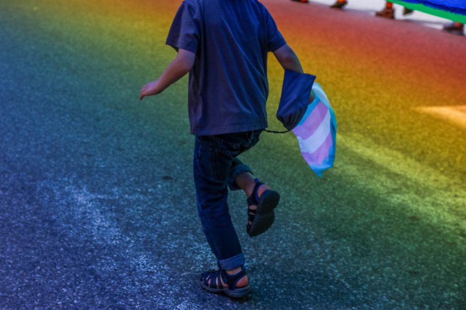 Un niño corre con la bandera trans en la mano.